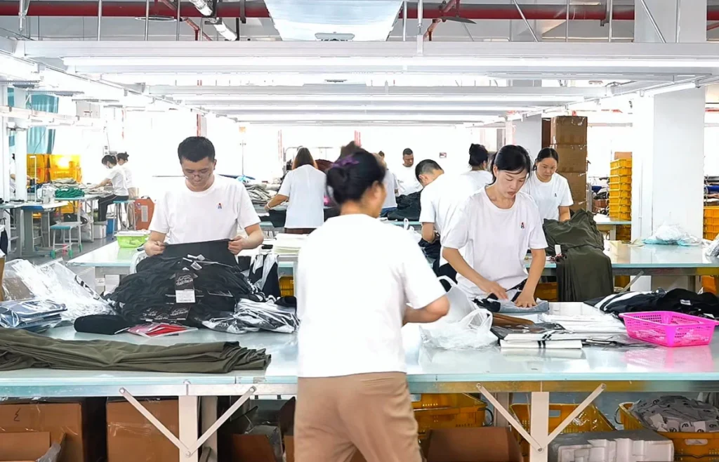 A professional activewear quality control inspection scene inside a clean garment factory, featuring a female quality inspector checking a sports bra on a worktable with measuring tape, inspection checklist, fabric swatches, labels, packaging samples, and neatly folded yoga apparel. Soft natural lighting, premium B2B activewear manufacturing style, clean modern factory background, realistic photography, editorial website blog hero image, 16:9 horizontal composition, no text, no logo, no watermark.